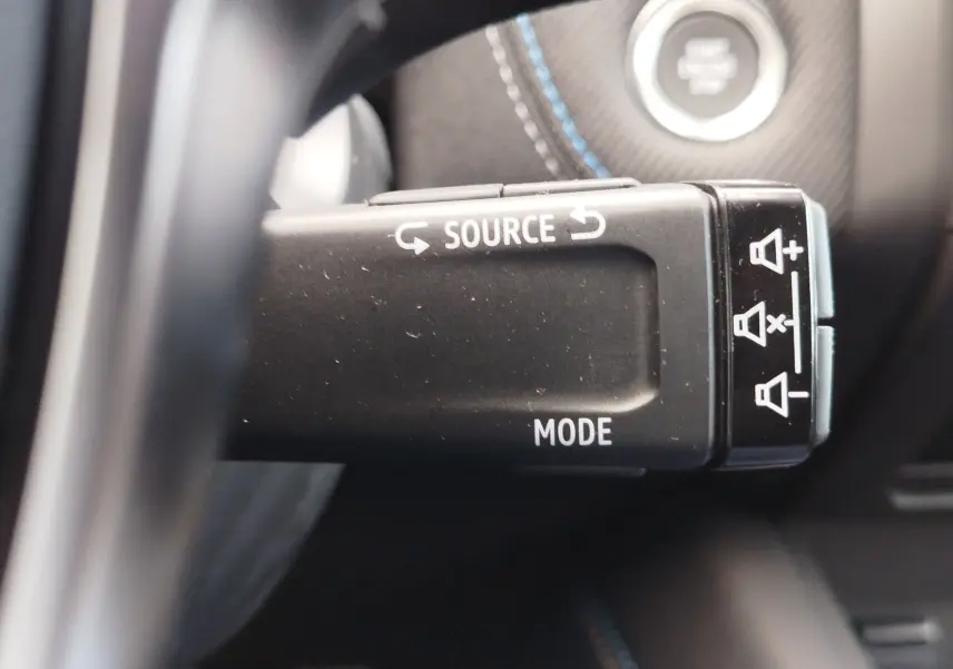 Gros plan sur la commande au volant noire du Renault Symbioz 2026, avec boutons source et mode visibles.
