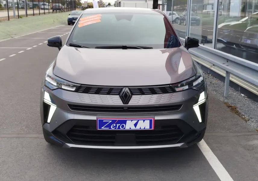Vue avant d'une Renault Symbioz gris cassiopée métal avec feux LED allumés et plaque Zéro KM visible.