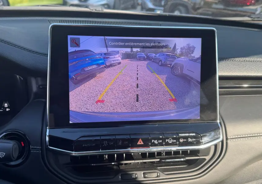 Écran tactile intérieur du Jeep Compass 2025 montrant la caméra de recul avec vue arrière sur un parking.