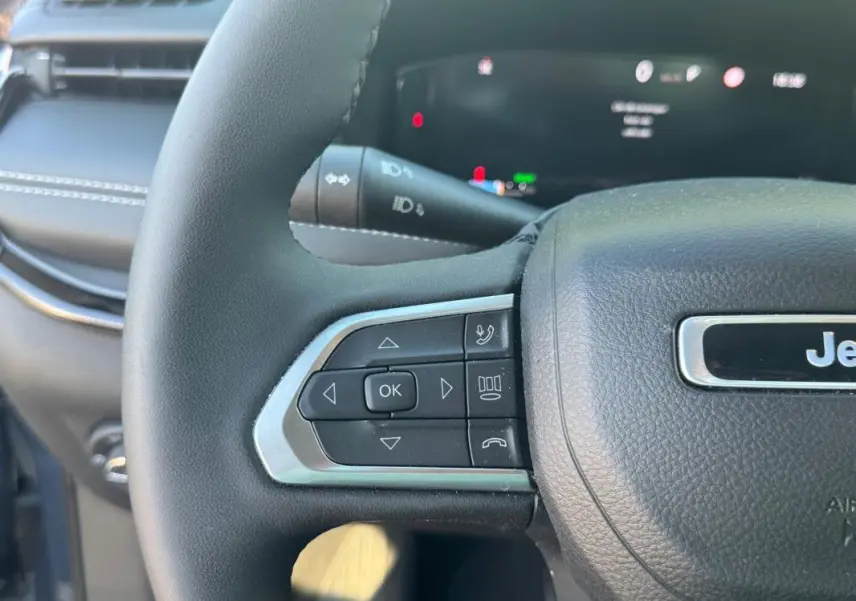 Gros plan sur le volant noir du Jeep Compass 2025, avec commandes intégrées et logo Jeep visible au centre.