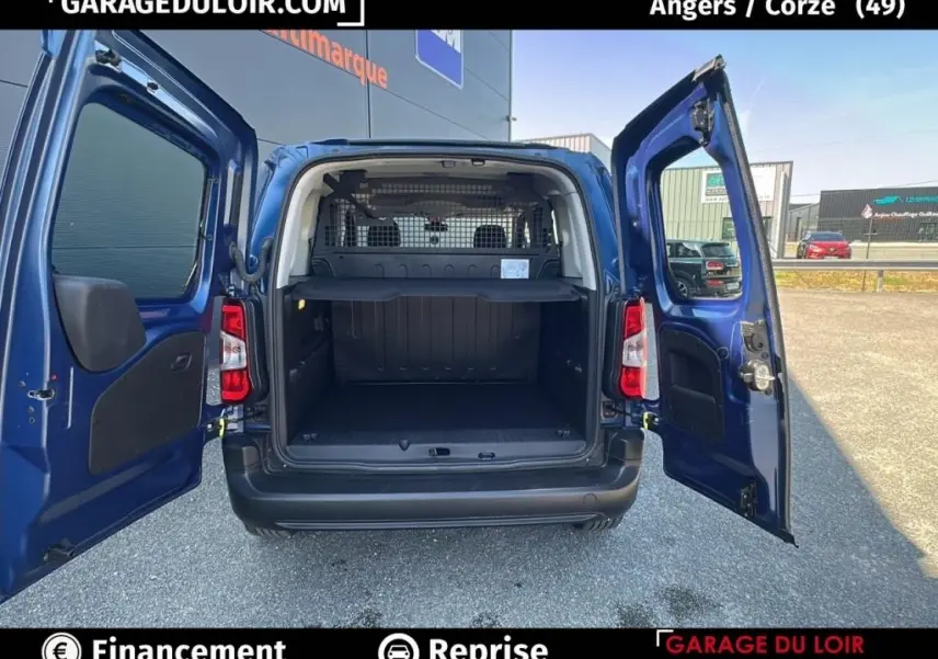 Vue arrière du Peugeot Rifter bleu 2024 avec portes ouvertes montrant le grand espace de chargement et la grille de séparation.