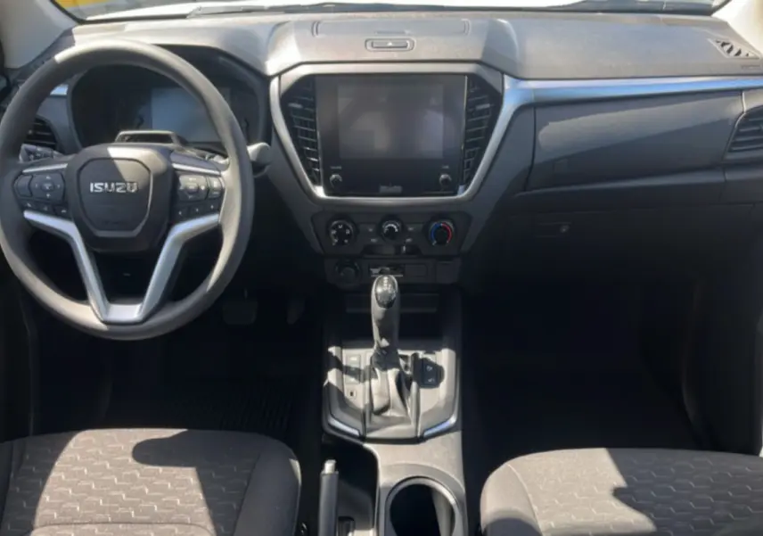 Vue intérieure avant de l'Isuzu D-MAX 2026, tableau de bord noir avec écran tactile et volant multifonctions.