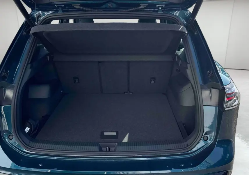 Coffre ouvert vu de l'arrière d'un Volkswagen Tiguan 2025 bleu, montrant l'espace de chargement vide et le hayon relevé.