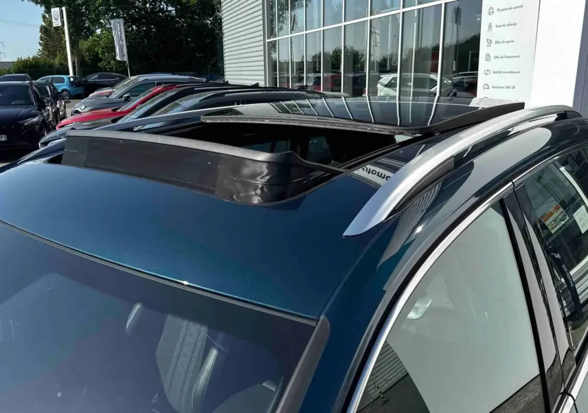 Toit ouvrant panoramique ouvert sur le côté gauche d’un Volkswagen Tiguan bleu 2025 en extérieur.
