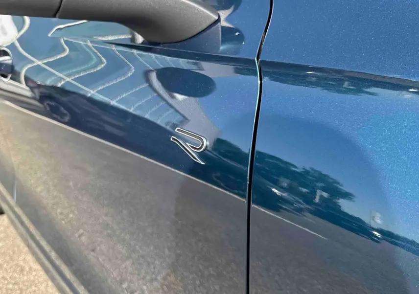 Gros plan sur la porte côté gauche du Volkswagen Tiguan bleu métallisé avec logo R distinctif.