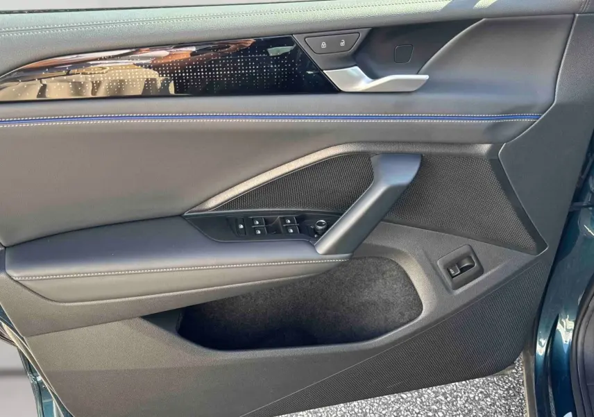 Vue rapprochée de la porte avant gauche du Volkswagen Tiguan 2025 bleu, avec garniture noire et surpiqûres bleues.