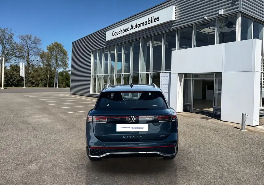 Vue arrière d'un Volkswagen Tiguan 2025 bleu garé devant un showroom Coudebec Automobiles.
