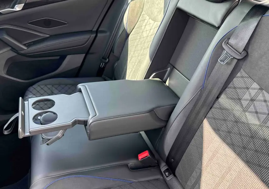 Vue rapprochée des sièges arrière noirs avec accoudoir central déployé et porte-gobelets du Volkswagen Tiguan 2025.