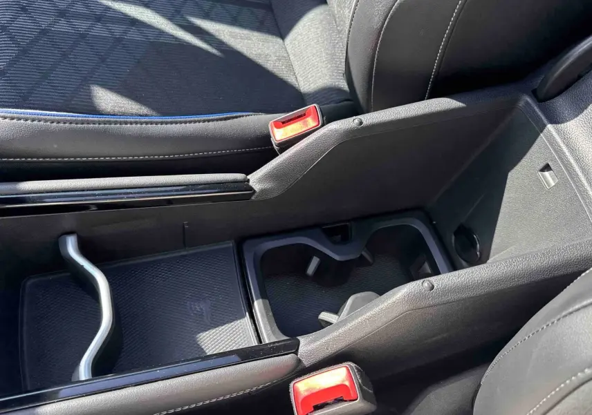 Gros plan sur la console centrale noire du Volkswagen Tiguan 2025, avec porte-gobelets et accoudoir en cuir.