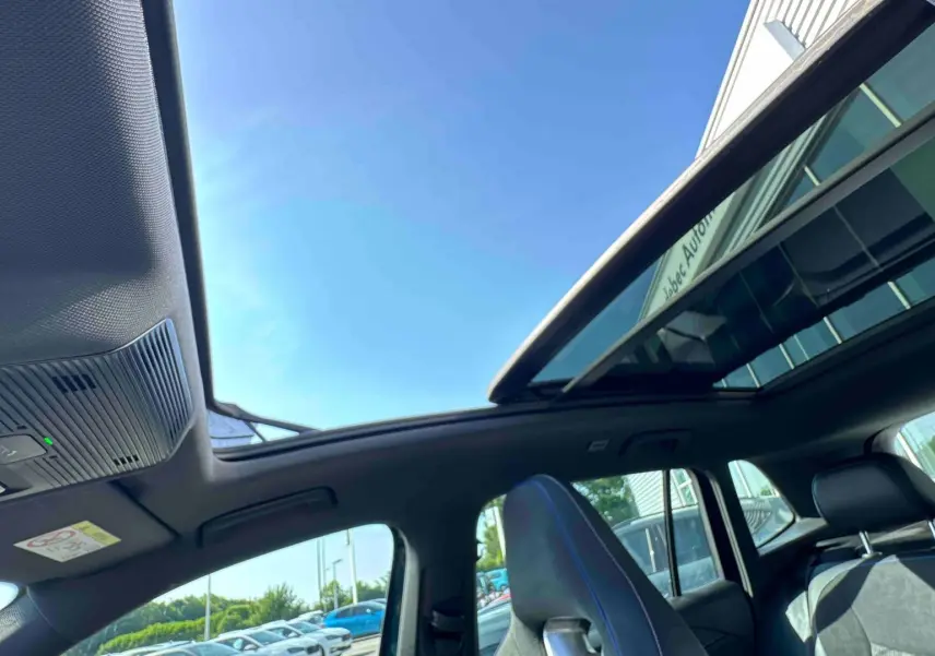 Vue intérieure du toit ouvrant panoramique et des sièges avant en cuir noir du Volkswagen Tiguan bleu 2025.