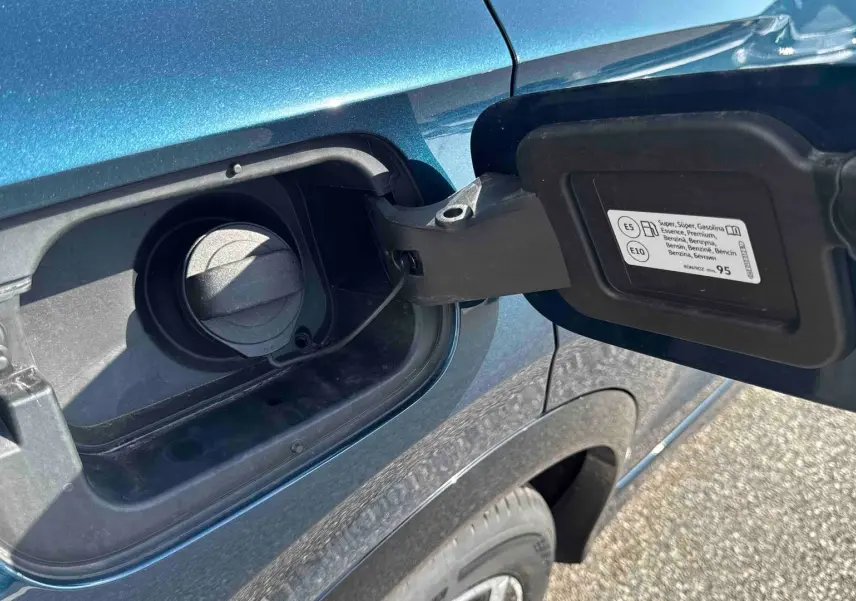 Bouchon de réservoir essence ouvert sur le côté gauche d’un Volkswagen Tiguan bleu métallisé, avec jante visible.
