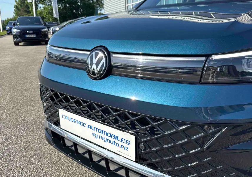 Gros plan sur l’avant bleu métallisé du Volkswagen Tiguan 2025 avec calandre ajourée et logo VW central.