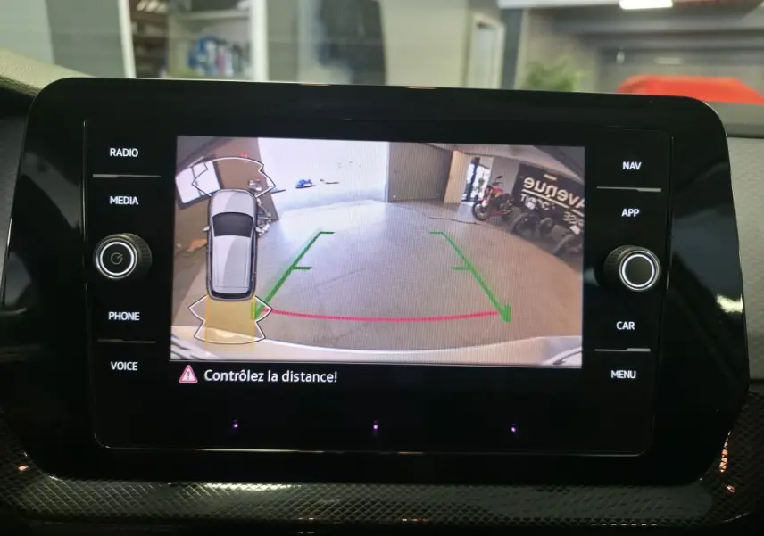 Écran de caméra de recul du Volkswagen T-Cross gris montrant l’arrière avec repères de distance en garage.