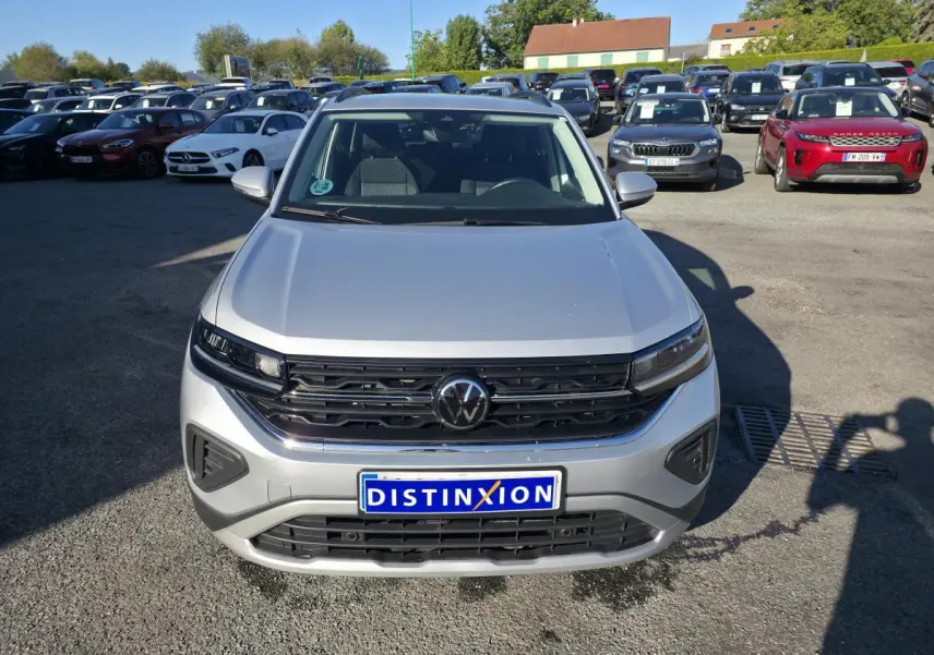 Volkswagen T-Cross gris métallisé vue de face, avec calandre noire et logo VW central bien visible.