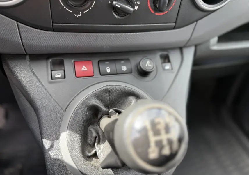 Gros plan sur le levier de vitesses manuel et les commandes centrales du tableau de bord intérieur du Peugeot Partner blanc de 2017.