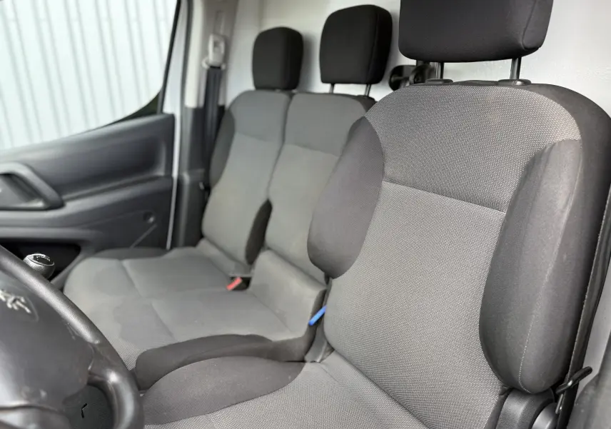 Vue intérieure côté conducteur du Peugeot Partner 1.5 HDI 75 de 2017, sièges tissu gris avec appuie-têtes noirs.