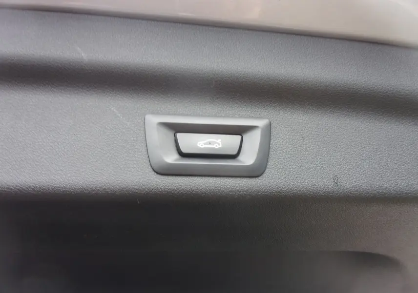 Bouton d'ouverture électrique du coffre sur panneau intérieur noir d'un BMW X1 argent métallisé 2024.
