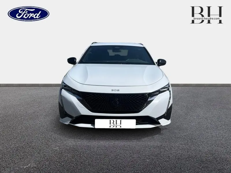 Vue frontale d'une Peugeot 308 SW PHEV 180ch GT blanche Okénite avec calandre noire et phares LED fins