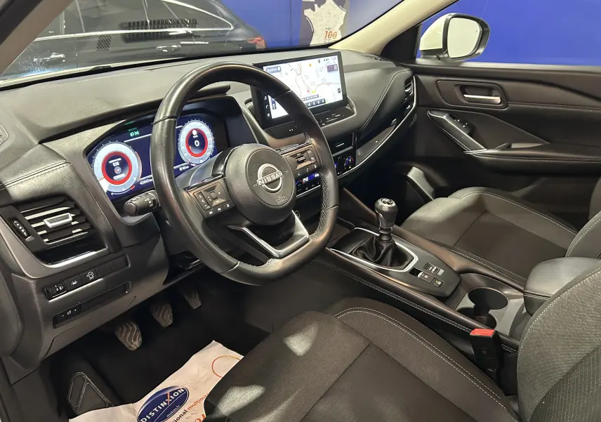 Vue intérieure côté conducteur du Nissan Qashqai 1.3 Hybrid 140 N-Connecta 2023, tableau de bord et volant visibles.