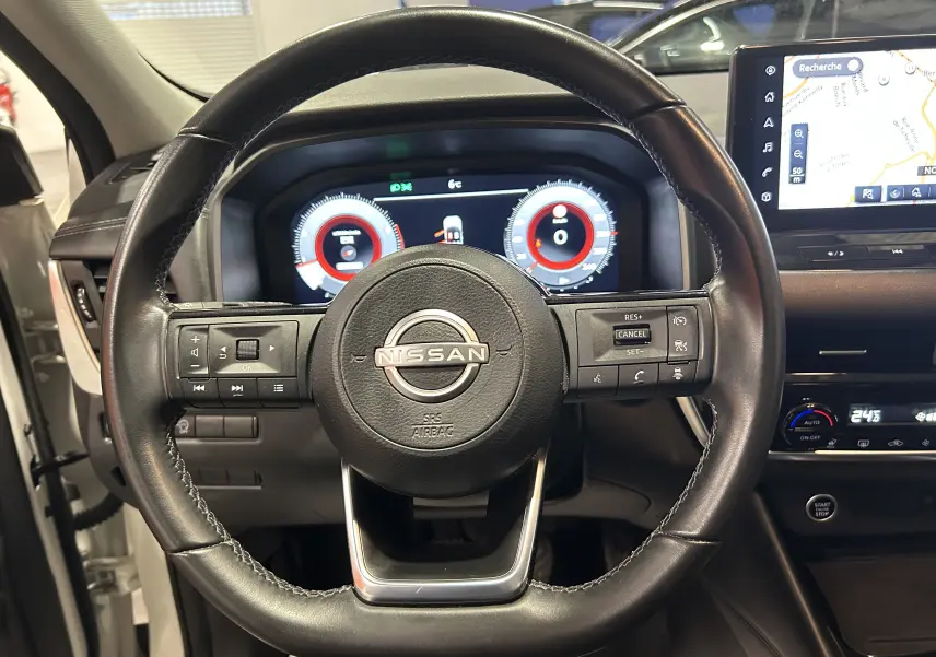 Vue centrée sur le volant cuir noir du Nissan Qashqai 2023 avec tableau de bord numérique et écran GPS visible.
