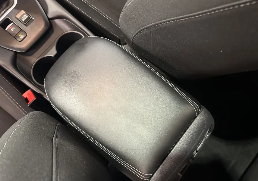 Vue rapprochée de l'accoudoir central en cuir noir avec surpiqûres blanches dans l'habitacle du Nissan Qashqai 2023.