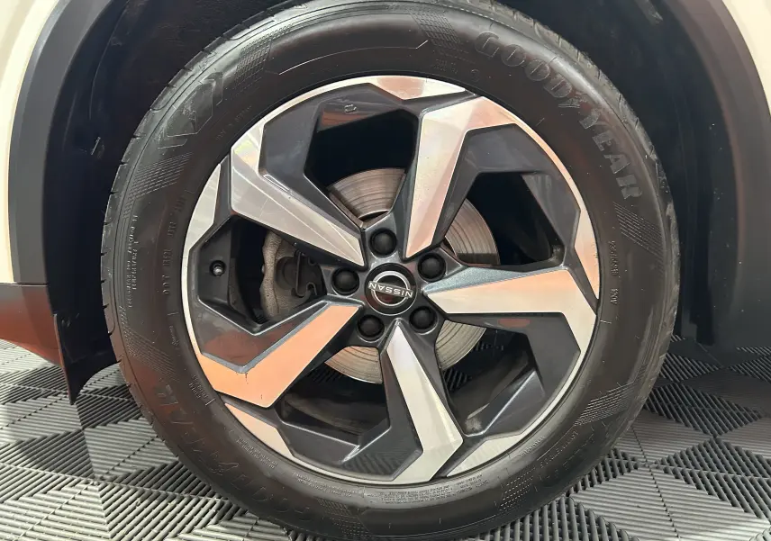 Gros plan sur la roue avant droite du Nissan Qashqai blanc lunaire, jante alliage bicolore et pneu Goodyear.