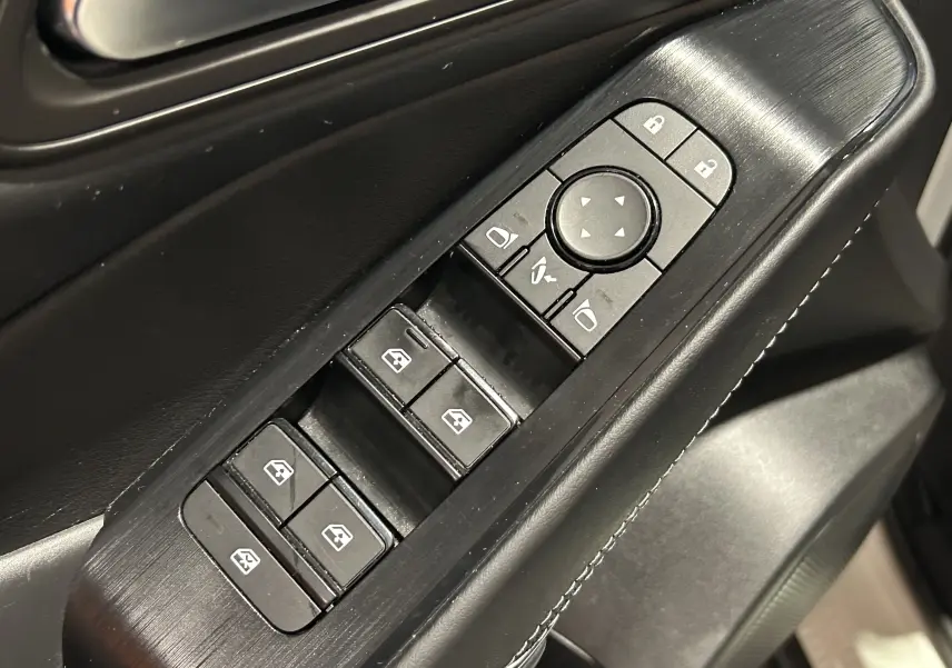 Gros plan sur les commandes des vitres et rétroviseurs côté conducteur du Nissan Qashqai 1.3 Hybrid 2023 en intérieur noir.