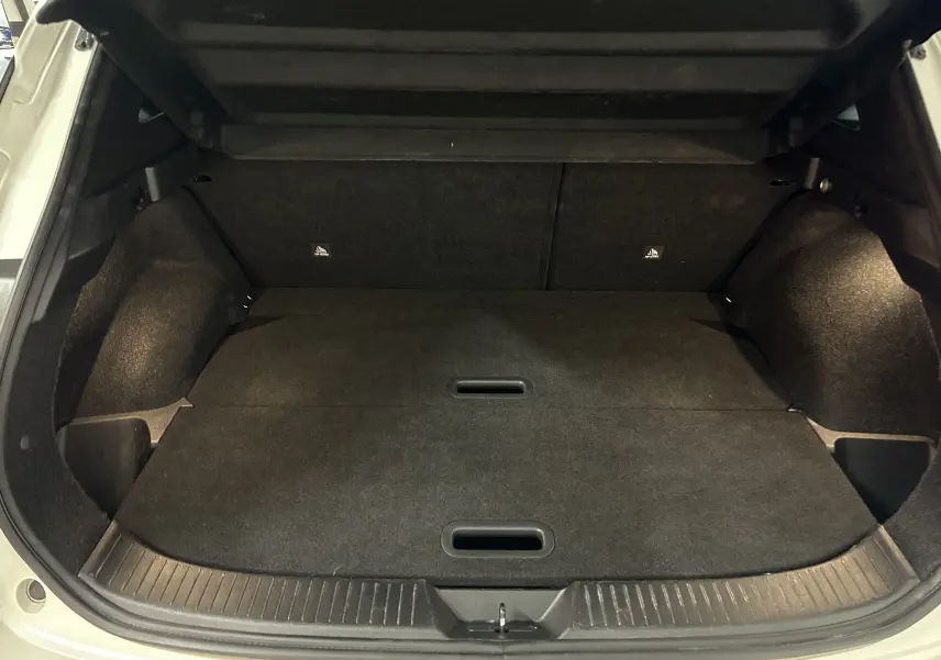 Coffre ouvert vu de l'arrière d'un Nissan Qashqai blanc lunaire, montrant un espace de chargement plat et noir.