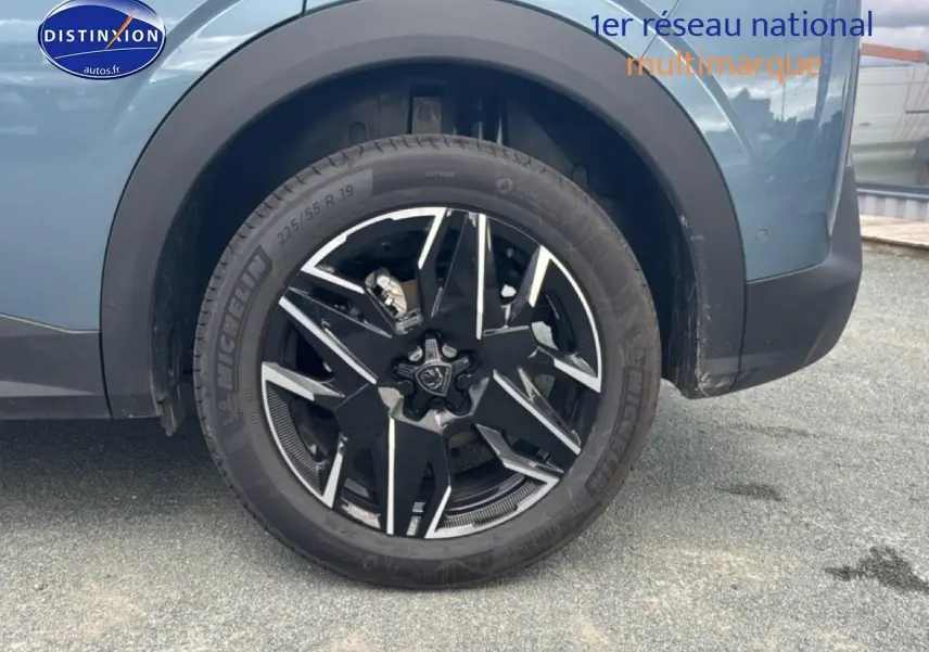 Gros plan sur la roue avant gauche avec jante alu noire et argentée du Peugeot 3008 bleu 2025.