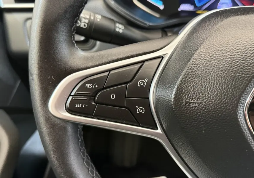 Gros plan sur les commandes de régulateur de vitesse au volant cuir noir de la Renault Clio Business E-Tech hybride 2021.