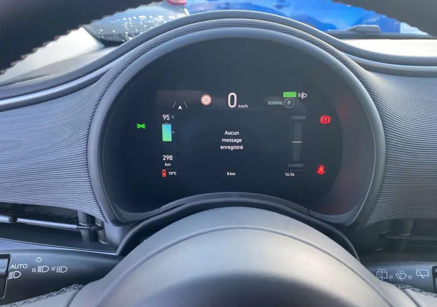 Vue rapprochée du tableau de bord numérique de la FIAT 500 électrique noire, affichant vitesse et autonomie.