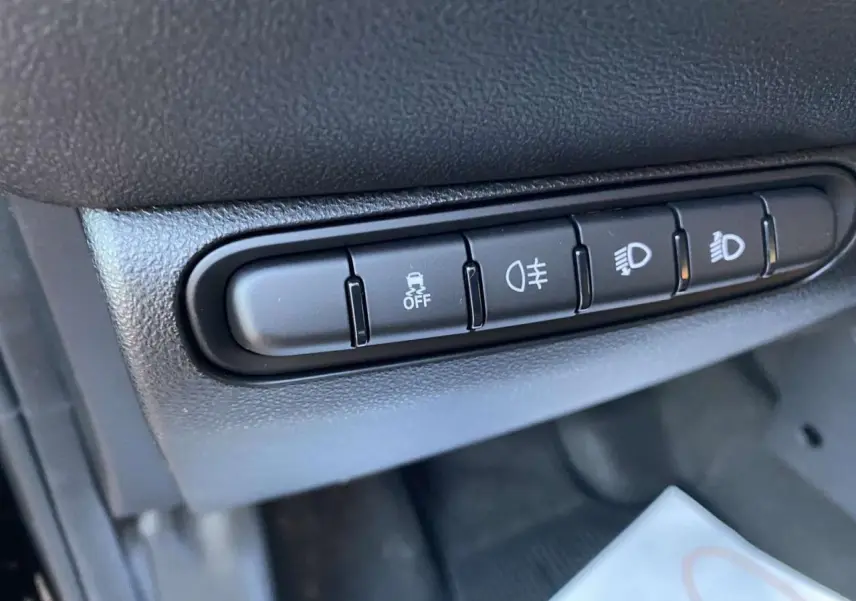 Gros plan sur les boutons de contrôle des feux et de l'ESP dans l'habitacle noir de la Fiat 500 électrique 2022.