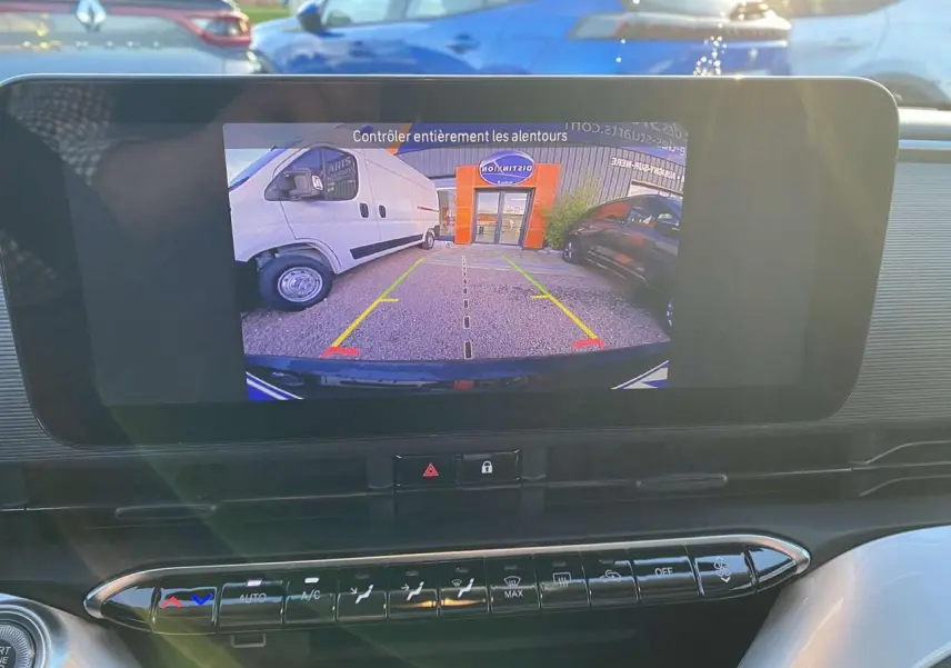 Écran central montrant la caméra de recul d'une Fiat 500 électrique noire, vue intérieure du tableau de bord.