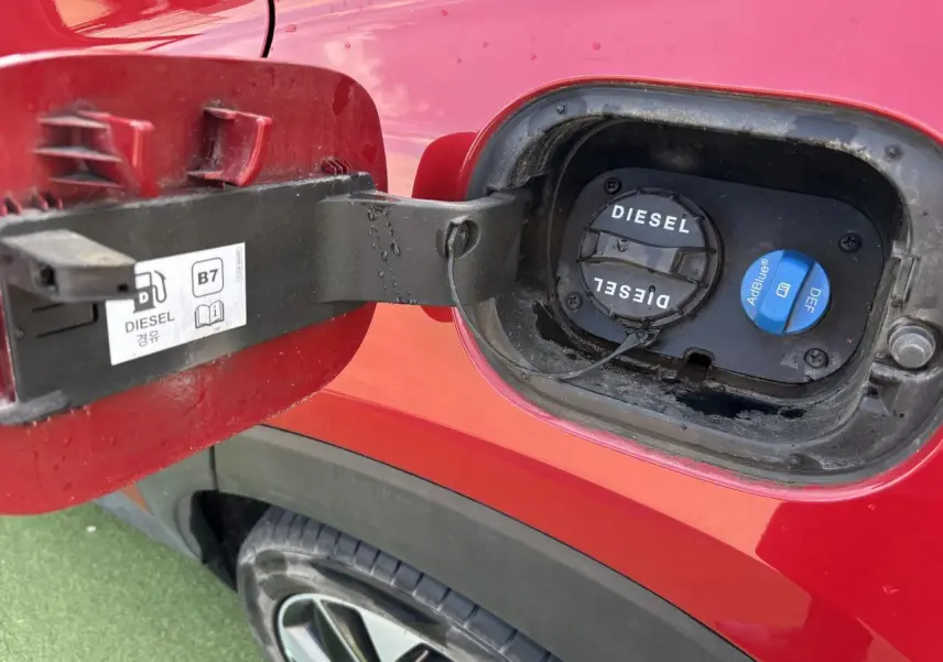 Gros plan sur la trappe à carburant côté gauche d'un Hyundai Tucson rouge métallisé, bouchons diesel et AdBlue visibles.