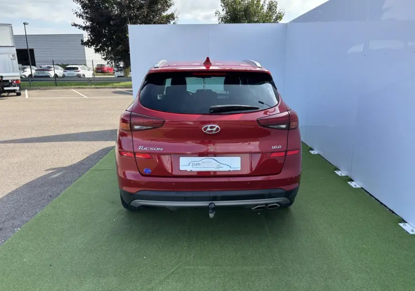 Vue arrière d'un Hyundai Tucson rouge métallisé 2020 avec attelage et double sortie d'échappement visible.