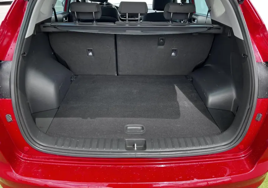Coffre ouvert vu de l'arrière d'un Hyundai Tucson rouge métallisé, montrant l'espace de chargement et la plage arrière.