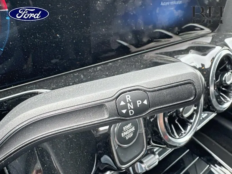 Gros plan sur la commande de boîte automatique et le bouton start/stop dans l'habitacle d'une Ford moderne noire.