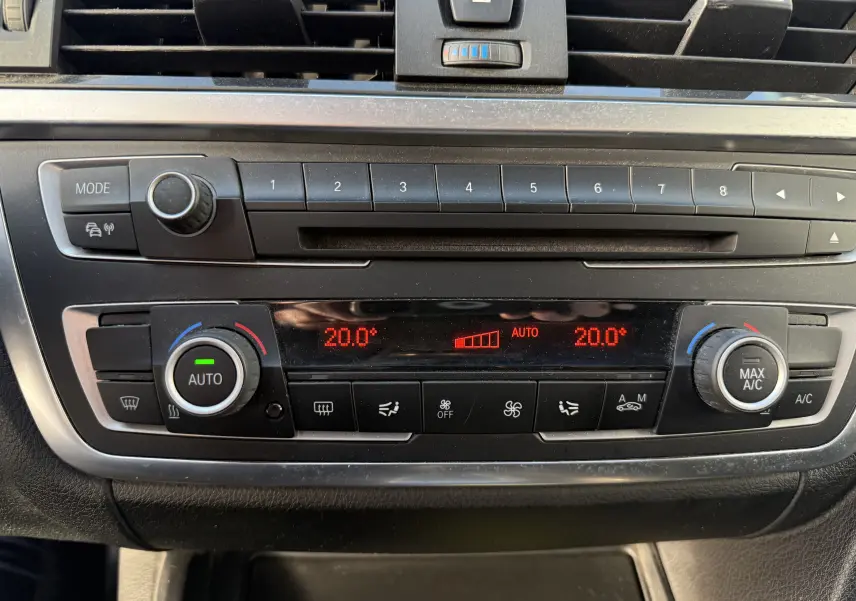Tableau de bord de BMW Série 3 320D 2013, zoom sur la climatisation automatique affichant 20°C en rouge.