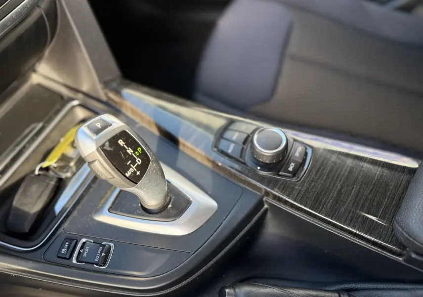 Gros plan sur le levier de vitesses automatique et la console centrale en finition bois sombre d'une BMW Série 3 320D gris.