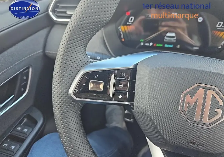 Gros plan sur le volant noir perforé du MG ZS Hybrid 2026, avec commandes intégrées et tableau de bord numérique en arrière-plan.