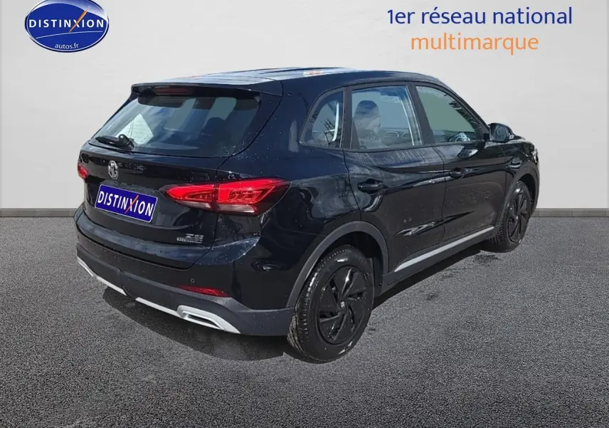 Vue 3/4 arrière droite du SUV noir MG ZS Hybrid 197 avec jantes noires et feux arrière LED allumés.