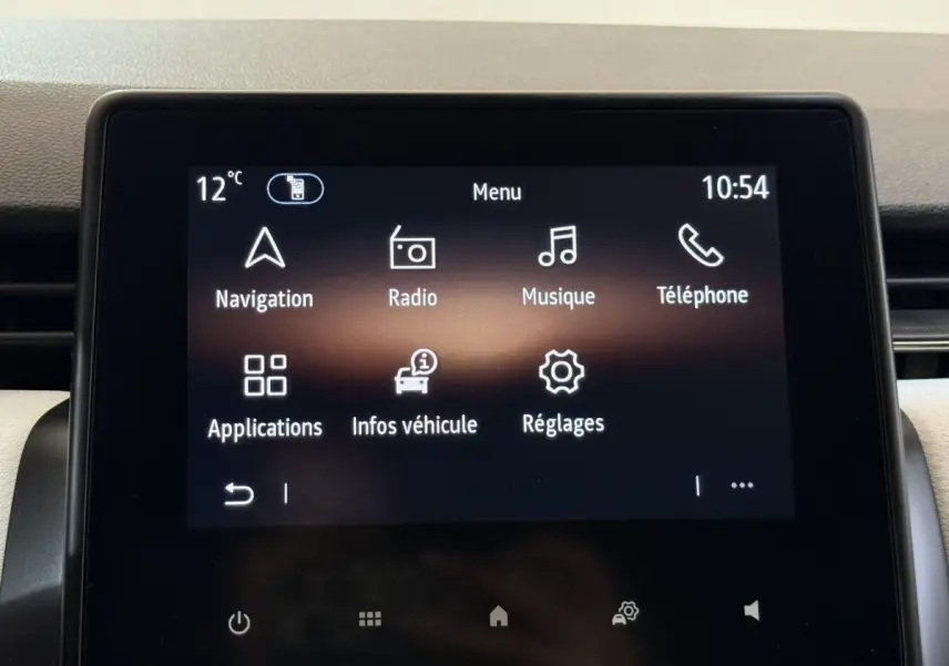 Écran tactile central de la Renault Clio blanche 2023 affichant le menu principal avec navigation et musique.