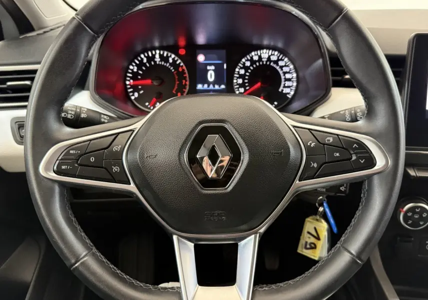 Vue centrée sur le volant cuir noir de la Renault Clio 2023 avec tableau de bord et commandes intégrées visibles.