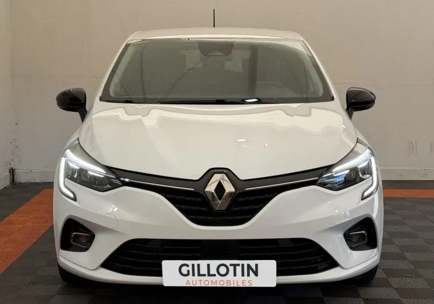 Vue avant d'une Renault Clio Evolution TCe 100 GPL blanche avec phares LED allumés et rétroviseurs noirs.