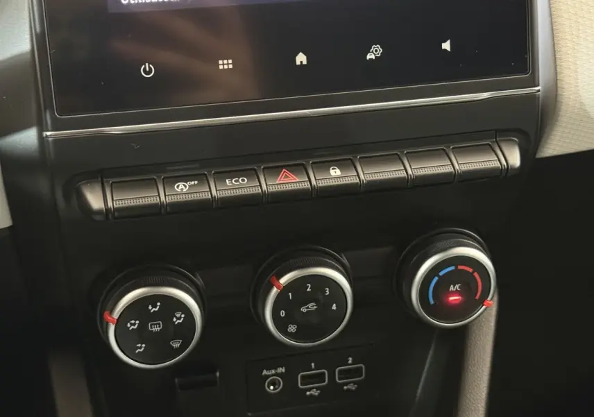 Gros plan sur la console centrale de la Renault Clio blanche 2023, montrant les commandes de climatisation et boutons multifonctions.