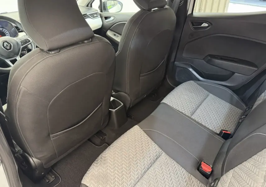 Vue intérieure arrière de la Renault Clio 2023, sièges tissu gris et noir avec motifs géométriques et portes noires.