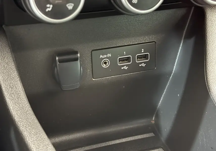 Vue rapprochée des ports USB et prise Aux-In noirs sur la console centrale de la Renault Clio blanche Evolution TCe 100 GPL.