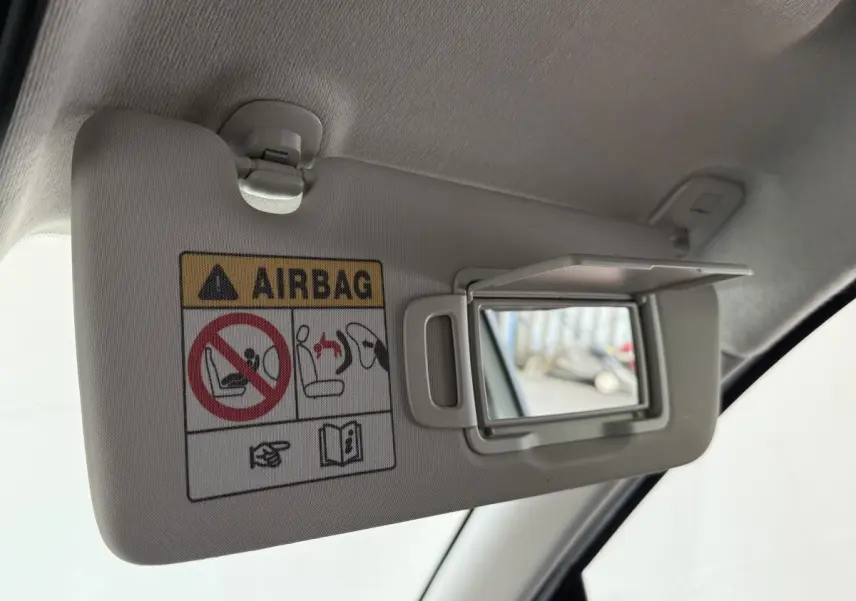Détail du pare-soleil côté conducteur avec miroir et avertissement airbag dans une Renault Clio blanche.
