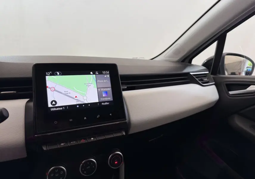 Vue intérieure côté passager de la Renault Clio blanche 2023, avec écran tactile de navigation affiché au centre du tableau de bord.