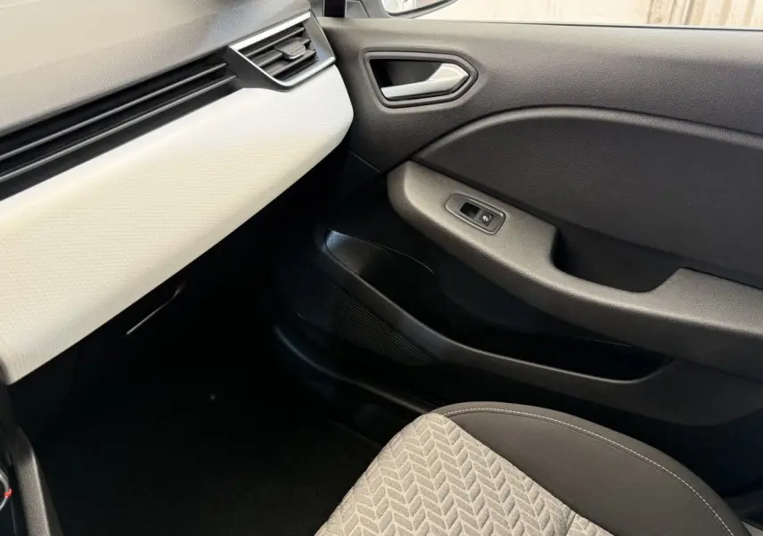 Vue intérieure côté passager avant de la Renault Clio Evolution TCe 100 GPL 2023 avec tableau de bord blanc et porte noire.